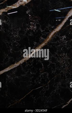 Elegant black marble surface with striking gold and white veining, suitable for modern interiors or artistic displays Stock Photo