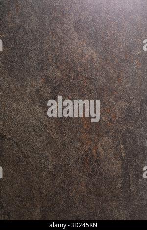 Dark textured stone surface with a unique pattern and natural variations observed in indoor lighting Stock Photo