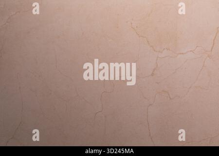 Textured beige stone surface with subtle cracks and patterns in natural light creates a calming atmosphere Stock Photo