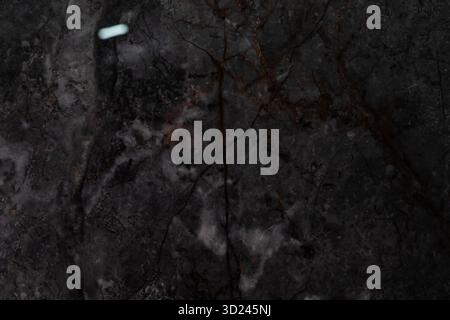 Dark marble surface with intricate veining patterns reflecting light softly and creating depth in an elegant setting Stock Photo