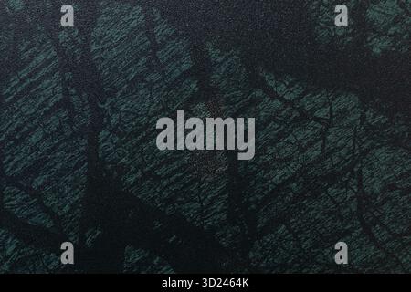 Dark textured surface with subtle patterns resembling natural stone in various shades of green and black Stock Photo