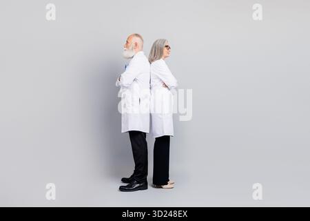 Two doctors stand back to back in white coats posing in a studio environment conveying professional healthcare and medical collaboration Stock Photo