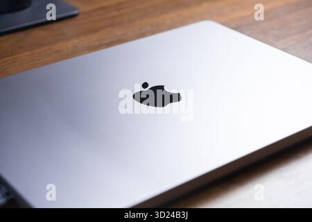 Poznan, Poland - September 18, 2025: Top-down close-up shot of a closed silver Apple laptop, its iconic logo clearly visible, resting on a rich wooden Stock Photo
