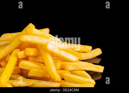 Crispy golden fried potatoes stacked on a black surface Stock Photo