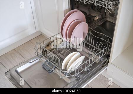 Open dishwasher with clean plates and bowls in kitchen setting Stock Photo