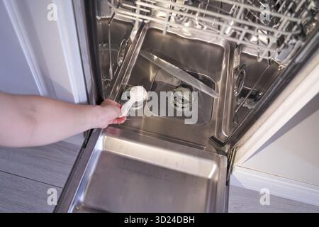Person loading dishwasher with detergent in open kitchen appliance Stock Photo