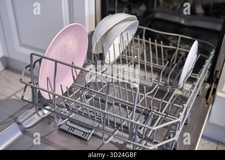 Open dishwasher with clean dishes inside kitchen appliance for efficient home Stock Photo