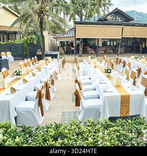 Beachfront wedding reception setup with elegant gold and white table decor Stock Photo