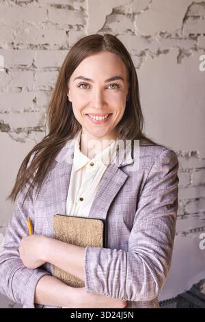 Confident caucasian female young adult smiling in professional attire holding Stock Photo