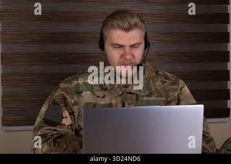 Man in military uniform using laptop outdoors Stock Photo