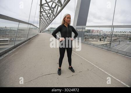 Confident woman in fitness attire on a modern bridge in the city Stock Photo