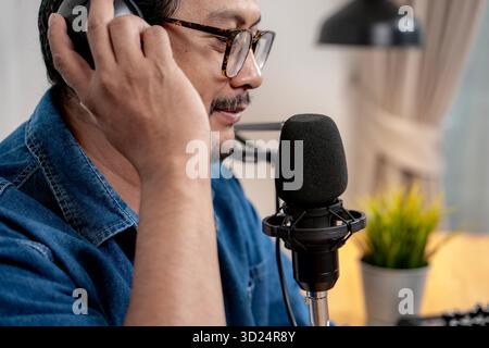 A young man recording a podcast in a modern studio with microphone and headphones, representing creativity, media, and communication. Stock Photo
