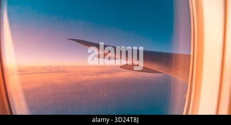 Picturesque sunset view from airplane window clouds peaceful sky aerial travel tourism flying vacation business transportation landscape scene Stock Photo