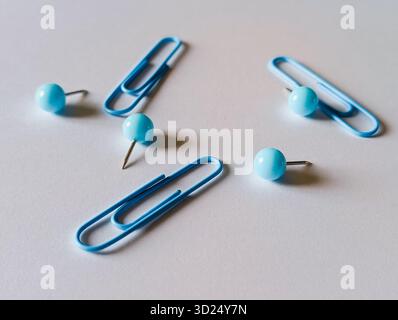 blue paper clips and push pins scattered on a white desk Stock Photo