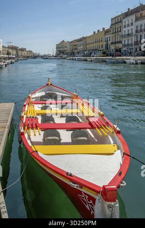 Close-up of a traditional, colorful wooden boat with the cross and the colors of Languedoc (red, yellow and green) with yellow-red oars on board, moor Stock Photo