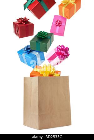 Many gift boxes falling into paper bag on white background Stock Photo