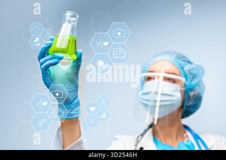 Scientist observes green liquid in flask for research purposes related to health and medicine Stock Photo