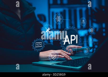 API Application Programming Interface concept. Person using laptop with digital gear icons, representing software integration, system connectivity, Stock Photo