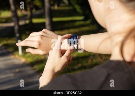 Poznan, Poland - September 24, 2025: A person's hand touches Apple Watch screen outdoors, displaying various app icons for comprehensive health and ef Stock Photo