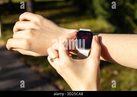 Poznan, Poland - September 24, 2025: Close-up of hands interacting with an Apple Watch showing a heart rate of Current 110 bpm, emphasizing personal w Stock Photo