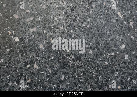 Close-up of a dark terrazzo surface with scattered light-colored chips Stock Photo