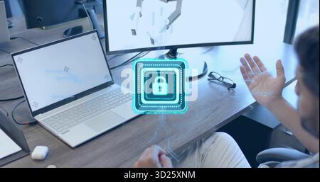 Gesturing man in shirt touching holographic lock icon above desk, with laptop, monitor, copy space Stock Photo