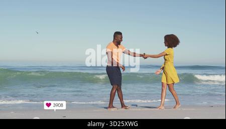 Walking barefoot couple holding hands on sandy beach with seagull, waves, floating heart icon Stock Photo