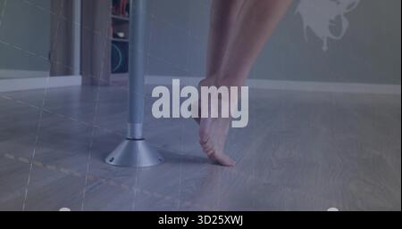 Balancing female dancer wearing dancewear standing en pointe on wooden dance floor, with metal pole Stock Photo
