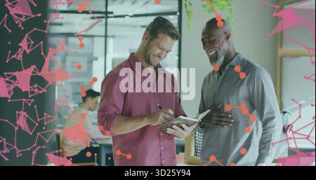Discussing project notes two men laughing and writing in open-plan office with pink network overlay Stock Photo