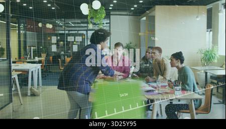 Presenting presenter leaning on green chair addressing four colleagues at office table, copy space Stock Photo