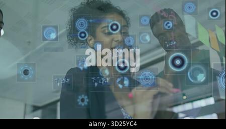 Touching curly-haired woman in blazer swiping display in office, target graphics and map Stock Photo