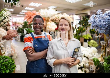 Two Smiling Florists Posing in Flower Shop with Digital Tablet Stock Photo