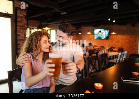 Couple drinking beer and eating snacks at the counter in a pub Stock Photo