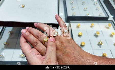 closeup of hand wearing two gold rings with diamond solitaire at jewelry store Stock Photo