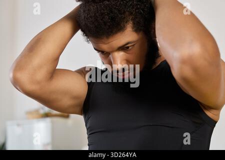 An athletic man adjusts his hair while getting ready to exercise at home. Stock Photo