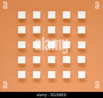 White sugar cubes arranged in rows on salmon orange background Stock Photo