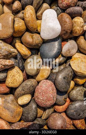 Artistic pebbles beach top closeup view, natural stone texture pattern background, minimalist coastal nature abstract Stock Photo