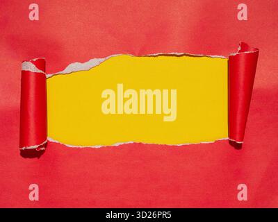 Red torn paper with rolled edges on a yellow background. Copy space. Stock Photo