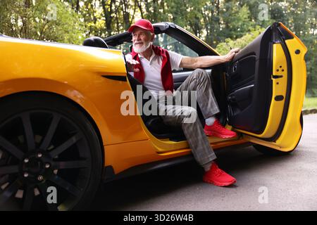 Stylish senior man getting out of modern cabriolet outdoors Stock Photo