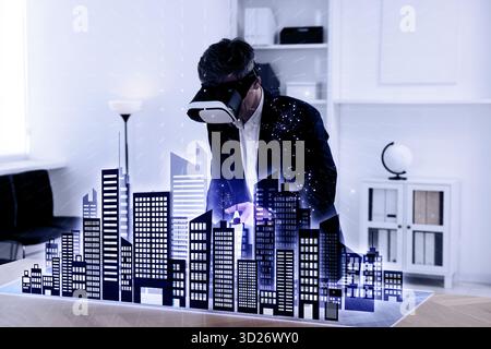 Man using virtual reality headset in office. Hologram of buildings in front of him. Modern technologies in architecture Stock Photo