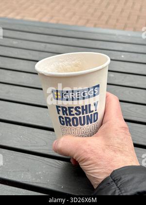 Cardiff, Wales, UK - 17 October 2025: Person's hand holding a cup of Greggs coffee in a disposable cup Stock Photo