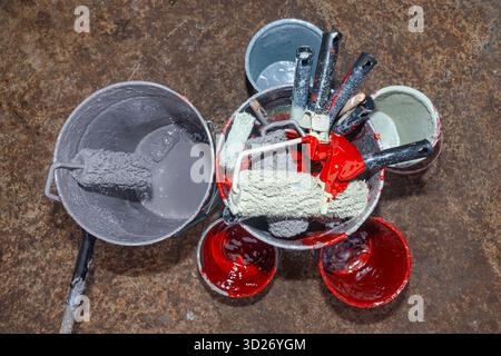 Empty paint buckets containing used rollers and brushes Stock Photo
