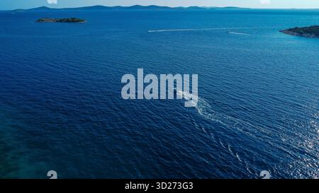 Powerful boat tracing a path of white foam across the vast, deep blue sea. Stock Photo