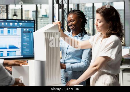 Real estate engineers work together on architectural 3D models details, collaborating on residential project strategy for a modern construction. Urban development for housing and infrastructure. Stock Photo