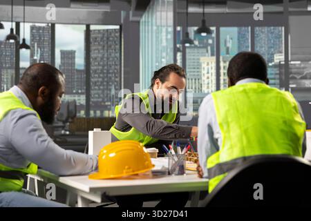 Architectural experts and contractors discussing construction and property design. The office meeting highlights teamwork, innovation, and planning for successful urban development. Stock Photo