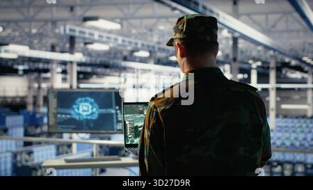 Military data center expert using ballistic missiles radar on laptop to watch for enemy threats. Army soldier in data center uses scanner tech to detect rockets launched by enemy troops, camera B Stock Photo
