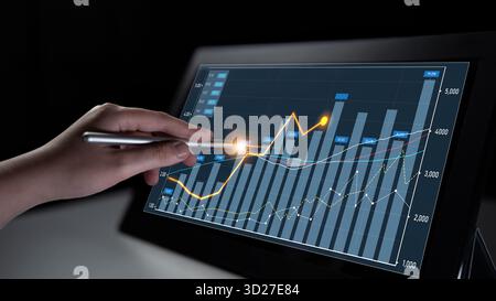 A hand interacts with a touchscreen display showcasing financial graphs and charts, highlighting data analysis and market trends in a dark setting. Sc Stock Photo