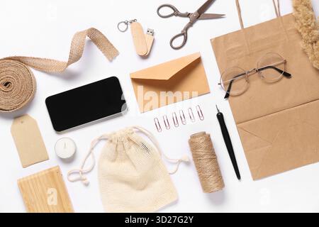 Composition with mobile phone, packaging items and delivery paper bag on white background Stock Photo