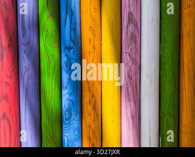 Background of aged wooden posts in various colors, with knots and cracks. Stock Photo