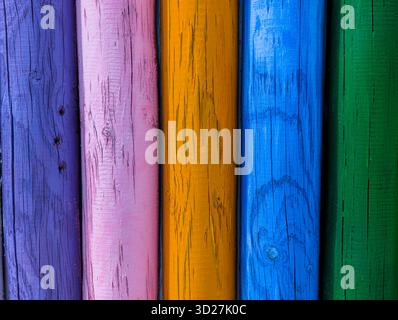 Background of aged wooden posts in various colors, with knots and cracks. Stock Photo
